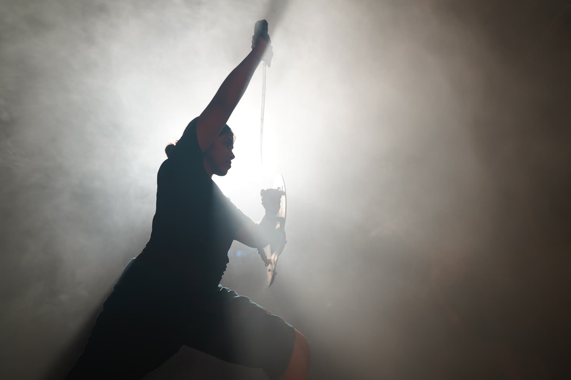 Silhouette of urumi practice in smoke-filled light